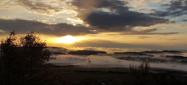 Sonnenuntergang mit Wolken und Nebel im Tal