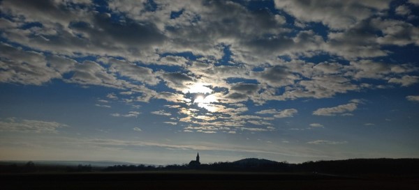 Wolkiger Himmel verdeckt die Sonne über die Kirche von Pécsely